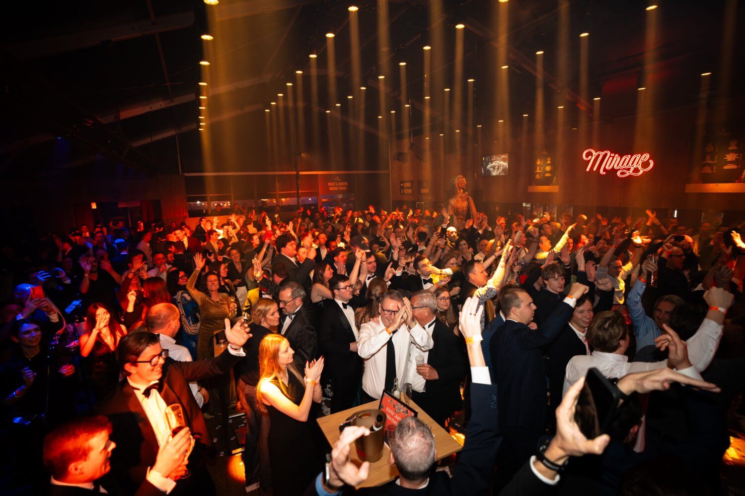 Feestende menigte onder dramatische lichtshow op een groot gala-evenement — eventfotografie door Nanou Verhoeven