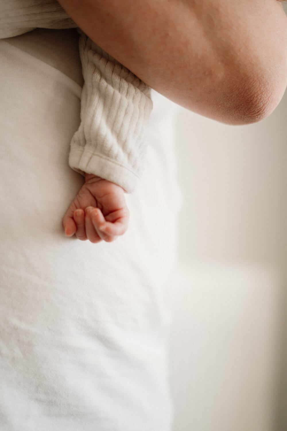 Pasgeboren vuistje op een wit dekentje — detail newbornfoto door Nanou Verhoeven
